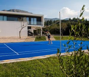 une femme frappant un ballon de tennis sur un court de tennis dans l'établissement Villa Holiness a luxury villa in Dubrovnik, tennis court, à Mlini