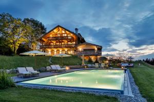 a large wooden house with a pool in front of it at Chiemsee Chalet in Frasdorf