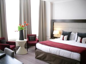 a hotel room with a large bed and chairs at Mercure Aberdeen Caledonian Hotel in Aberdeen