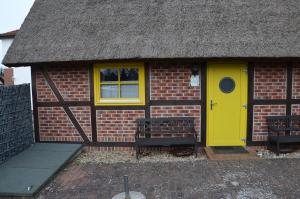 een bakstenen gebouw met een gele deur en twee banken bij Alte Scheune Koserow App. 1 in Ostseebad Koserow