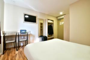 - une chambre avec un lit, un bureau et une télévision dans l'établissement B&B HOTEL Bollène, à Bollène