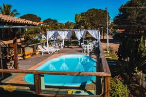 a swimming pool with a table and chairs next to a resort at Pousada Pargos in Itaúnas