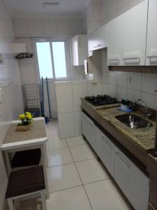 Apartamento Praia Grande في برايا جراندي: مطبخ أبيض مع حوض وموقد