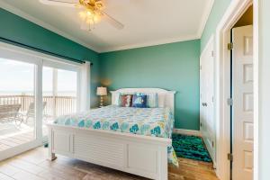 a bedroom with a bed with blue walls and a patio at License to Chill in Dauphin Island