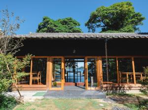 ein Haus mit Glastüren und einer Veranda in der Unterkunft sea-auberge shitsumi 海のオーベルジュ志積 in Obama