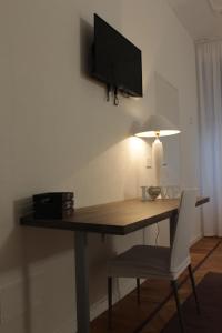 a desk with a television on a wall with a chair at MY BED affittacamere in Cuneo