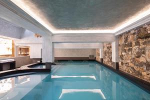 a swimming pool in a house with a stone wall at Hotel La Chaudanne in Méribel