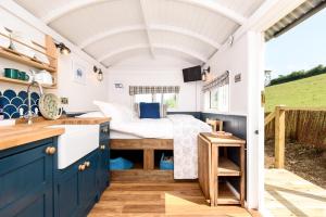 a bedroom in a tiny house with a bed at Penlea Retreat Luxury Coastal Shepherds Hut 5 Minute Walk to Pubs and Village in Polperro