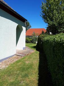 Haus Ebel في Putgarten: تحوط بجوار مبنى أبيض مع مسار