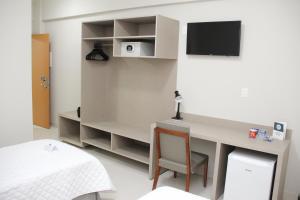 a room with a desk with a bed and a tv at Gran Park Hotel e Convenções in Mineiros