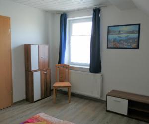 Zimmer mit einem Stuhl und einem Fenster mit blauen Vorhängen in der Unterkunft Ferienhaus Niesky in Niesky