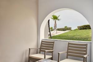 two chairs sitting on a balcony with a palm tree at Atlantica Marmari Palace in Mastichari