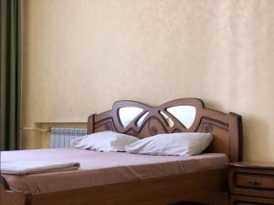 ドニプロにあるElit Aparts on Puskina WIFIのベッド(木製ヘッドボード、白い枕付)