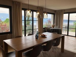 uma sala de jantar com mesa, cadeiras e janelas em Vue exceptionnelle sur lac d'Annecy et Montagnes em Menthon-Saint-Bernard