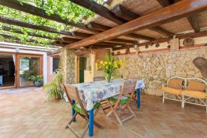 un patio con mesa, sillas y pared de piedra. en Villa Teresa 3 Abitaz Indipend Ti, en Bari Sardo