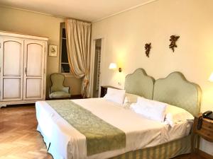 La Vittoria Boutique Hotel في غارْدا: غرفة نوم بسرير كبير وكرسيين