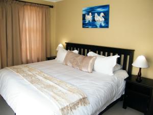sypialnia z łóżkiem z białą pościelą i poduszkami w obiekcie Absolute Cornwall Bed and Breakfast w mieście East London