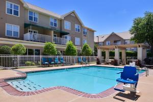 einen Pool mit Stühlen und ein Gebäude in der Unterkunft Staybridge Suites Wichita Falls, an IHG Hotel in Wichita Falls