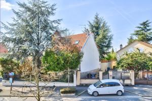 a white car parked in front of a house at Le Palmier - Cosy Appartement à 15 min de Paris in Deuil-la-Barre