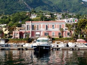 boats are docked in the water near a large building at Hotel Villa Svizzera Terme in Ischia