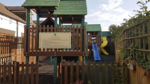 a playground with a wooden fence and a sign at The Elm Tree Inn in Wisbech