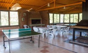 Habitación con mesas de ping pong y sillas blancas. en Yerba Buena casas de campo - Nono, en Nono