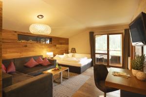 a hotel room with a couch and a bed at Almhof Family und Wellness Resort in Gerlos