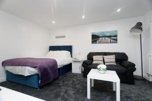 een slaapkamer met een bed, een bank en een tafel bij AMIRI HOUSE APARTMENTs in Leeds