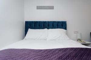 een slaapkamer met een groot bed met een blauw hoofdeinde bij AMIRI HOUSE APARTMENTs in Leeds