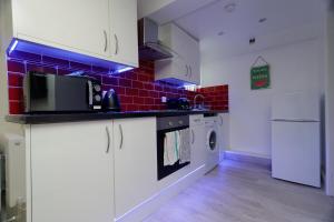 uma cozinha com armários brancos e uma parede de tijolos vermelhos em AMIRI HOUSE APARTMENTs em Leeds