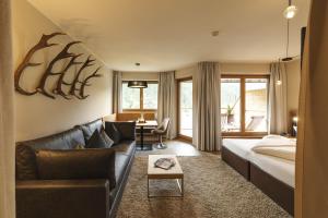 a hotel room with a couch and a bed and a table at Almhof Family und Wellness Resort in Gerlos +119 photos