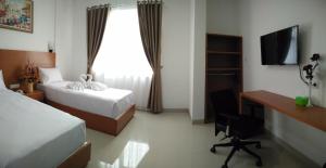 Habitación de hotel con 2 camas, escritorio y ventana en PETA HOSTEL Bandung, en Bandung