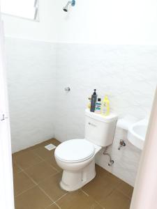 La salle de bains blanche est pourvue de toilettes et d'un lavabo. dans l'établissement Apartment Servis UITM Puncak Alam, à Bandar Puncak Alam