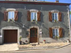 a gray building with windows and doors and flowers at Centre Sérénité au Coeur du Limousin in Fromental