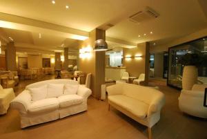 un soggiorno con divani bianchi e una sala da pranzo di Hotel Bracciotti a Lido di Camaiore