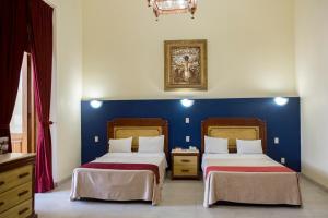 2 camas en una habitación con paredes azules en Hotel San Francisco Plaza, en Guadalajara