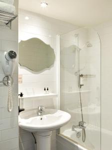 a white bathroom with a sink and a shower at Hotel Paradis in Paris