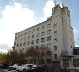 a white building with cars parked in front of it at Отель "Курган" in Kurgan