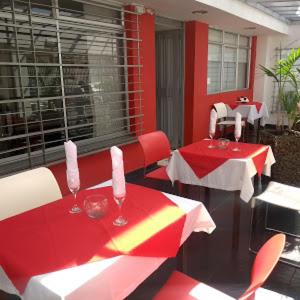 un restaurante con mesas y sillas rojas y blancas en Hotel TuKasa Inn, en Bogotá