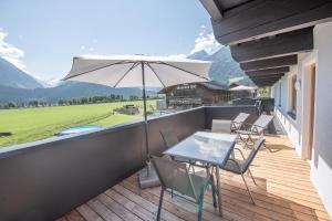 einen Balkon mit einem Tisch, Stühlen und einem Sonnenschirm in der Unterkunft Gästehaus Dreier in Neukirchen am Großvenediger