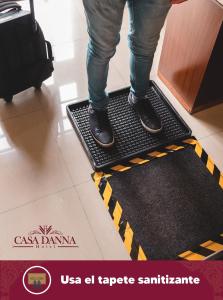 una persona de pie en una alfombra de bienvenida en el suelo en Hotel Casa Danna en Colima