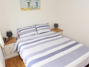 a bedroom with a bed with blue and white stripes at Ogof Aberporth in Aberporth