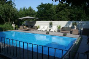 - une piscine avec des chaises, des tables et un parasol dans l'établissement Villa Wambach, à Tegelen