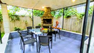 a man sitting at a table on a patio with a fireplace at Nita Apartment in K'obulet'i