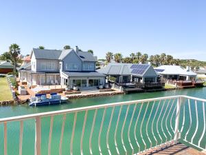 a row of houses on the water next to a river at Marina Martinique B&B in Jeffreys Bay