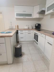 a kitchen with white cabinets and a trash can at Gemütlich ruhig und zentral durch Bahnhof in Bordesholm