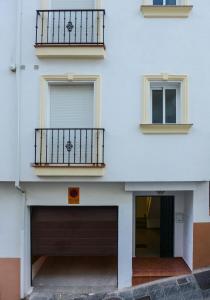 a white building with a garage and two balconies at Guejar Sierra House with Spectacular Views in Güéjar-Sierra
