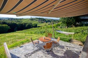 eine Terrasse mit einem Tisch und Stühlen unter einem großen Sonnenschirm in der Unterkunft House Thara Studio Apartments in Štrigova
