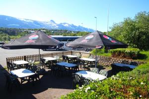 eine Gruppe von Tischen und Stühlen mit Sonnenschirmen in der Unterkunft Napoli Resturant & Hotell AS in Sandnessjøen