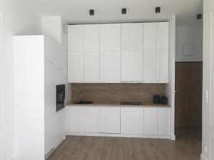 uma cozinha com armários brancos e um lavatório em Mlociny Apartment em Varsóvia